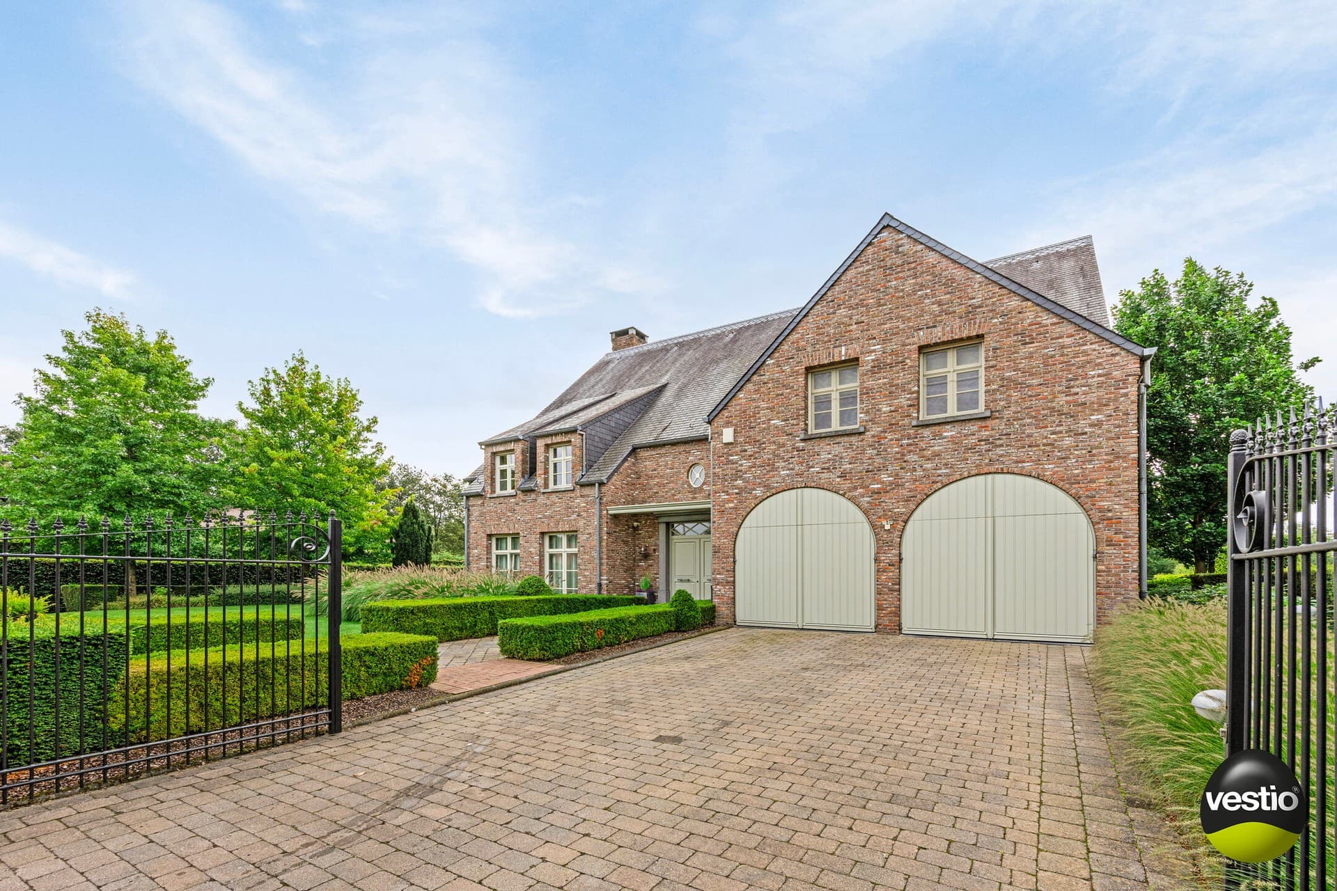 Landhuis met binnenzwembad en mutifunctioneel bijgebouw in residentiële omgeving.